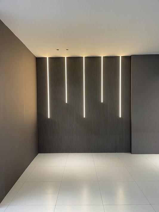 Modern interior feature wall with vertical smart LED strip lights installed on fluted wall panels, creating elegant ambient accent lighting for contemporary residential or commercial spaces