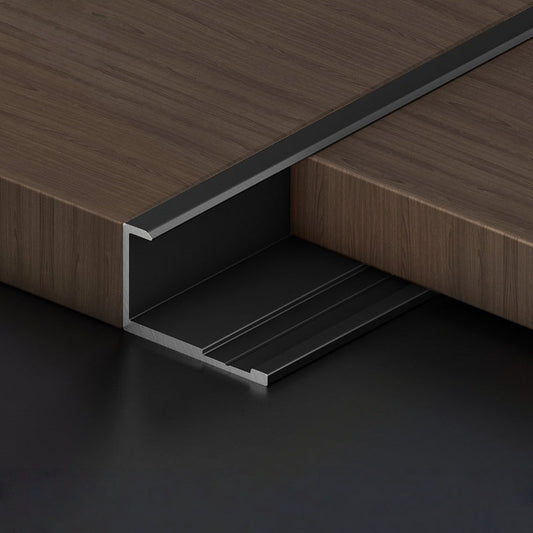 Black aluminum wall panel trim channel installed between wood panels, forming a clean recessed joint for modern interior wall panel installations