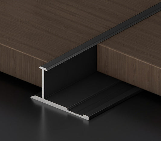 Black aluminum T-profile trim installed between wood panels for recessed LED strip lighting, creating a clean flush transition for modern interior wall and panel designs